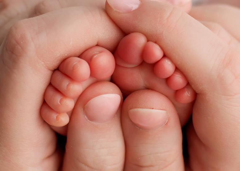 Close up of a newborn's toes cradled in a parent's hands.